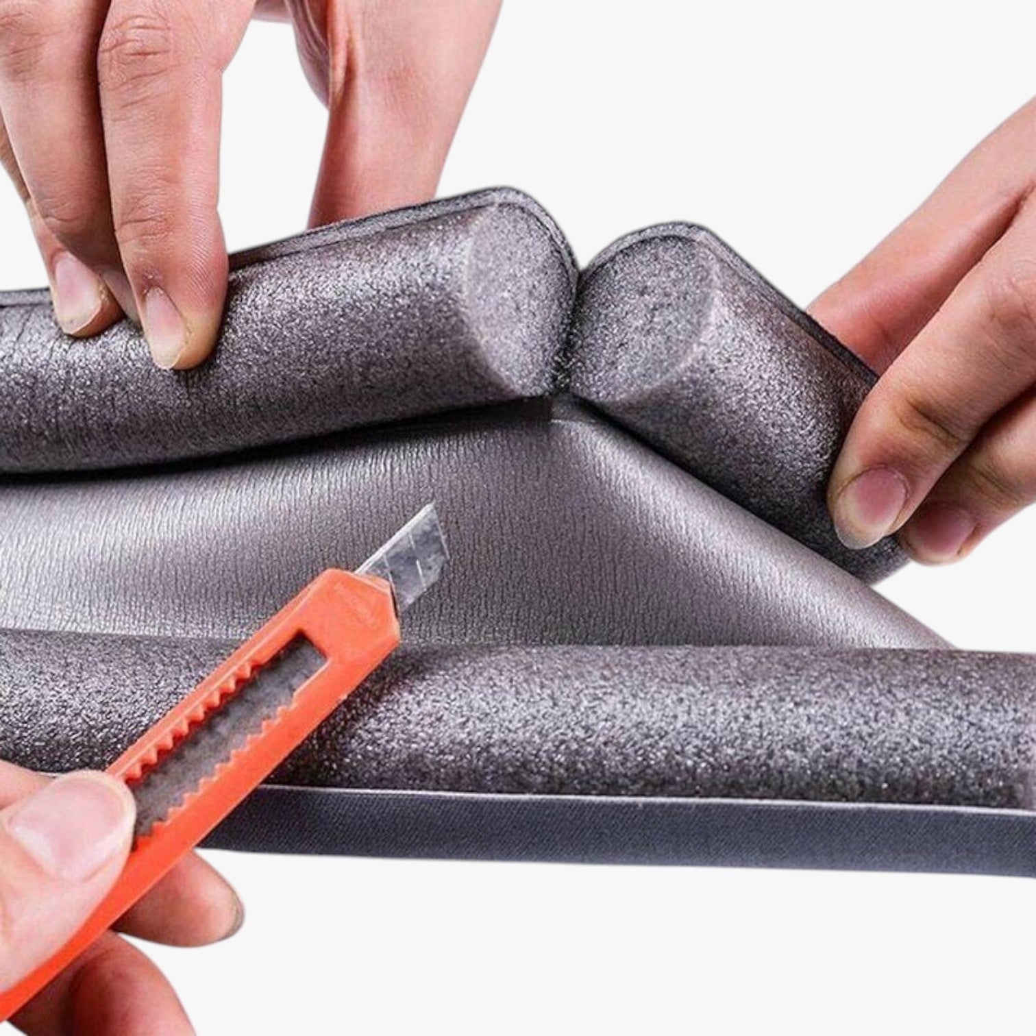 Roselva double-sided foam door weather stripping being trimmed with a utility knife for a custom fit
